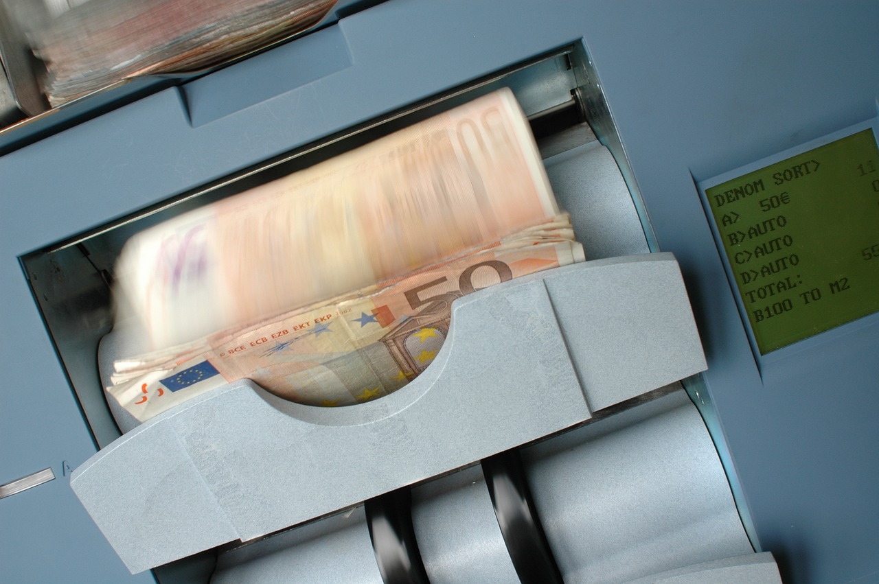Banknotes being counted in a high-speed money counting machine, with euro bills in motion inside the device.