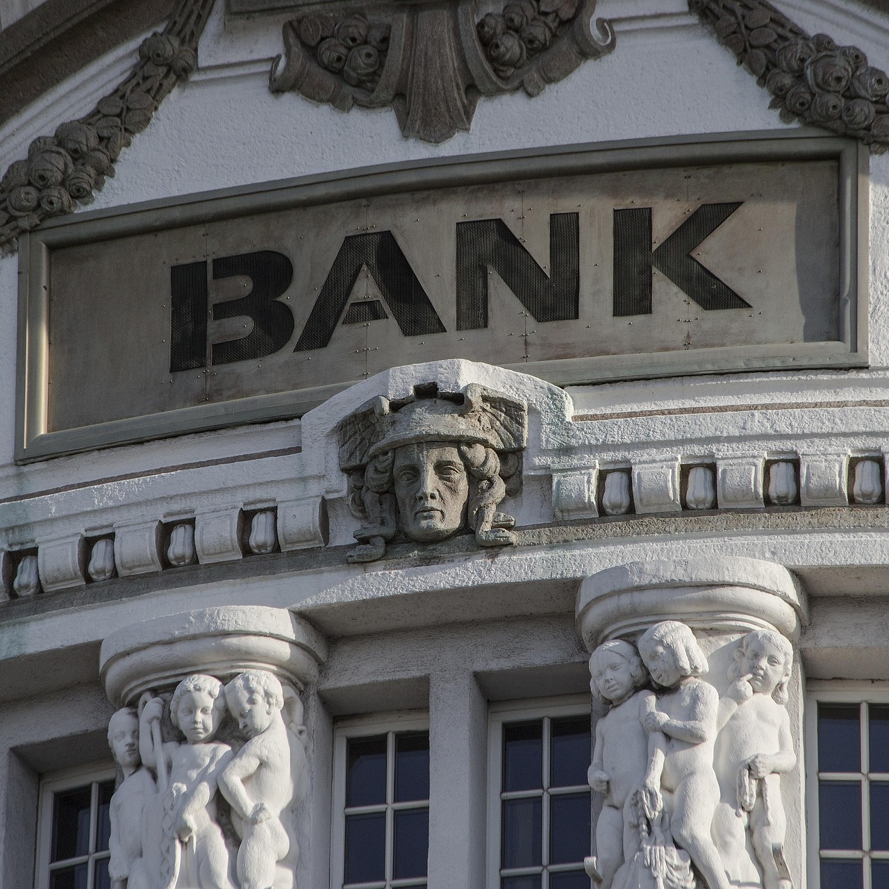 Historic stone bank building with engraved "BANK" sign and decorative sculptures.