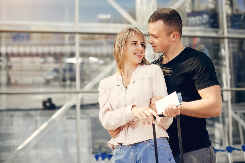 Couple in a airport. Beautiful blonde in a white jacket. Man in a black t-shirt