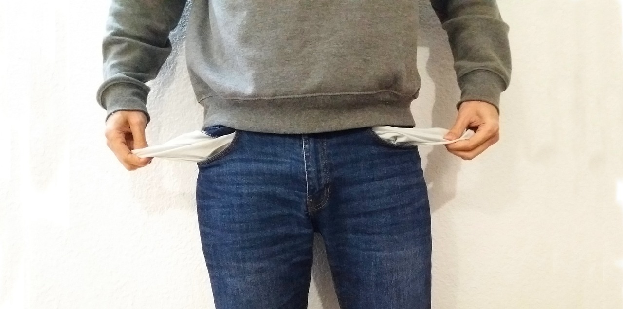 A man showing empty pockets, symbolizing financial hardship and overwhelming debt.
