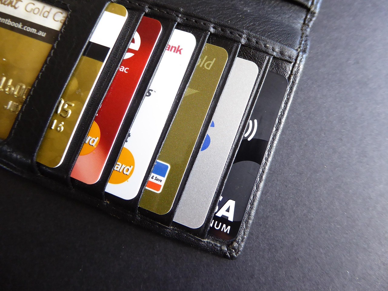 Multiple credit and debit cards organized in a black leather wallet.