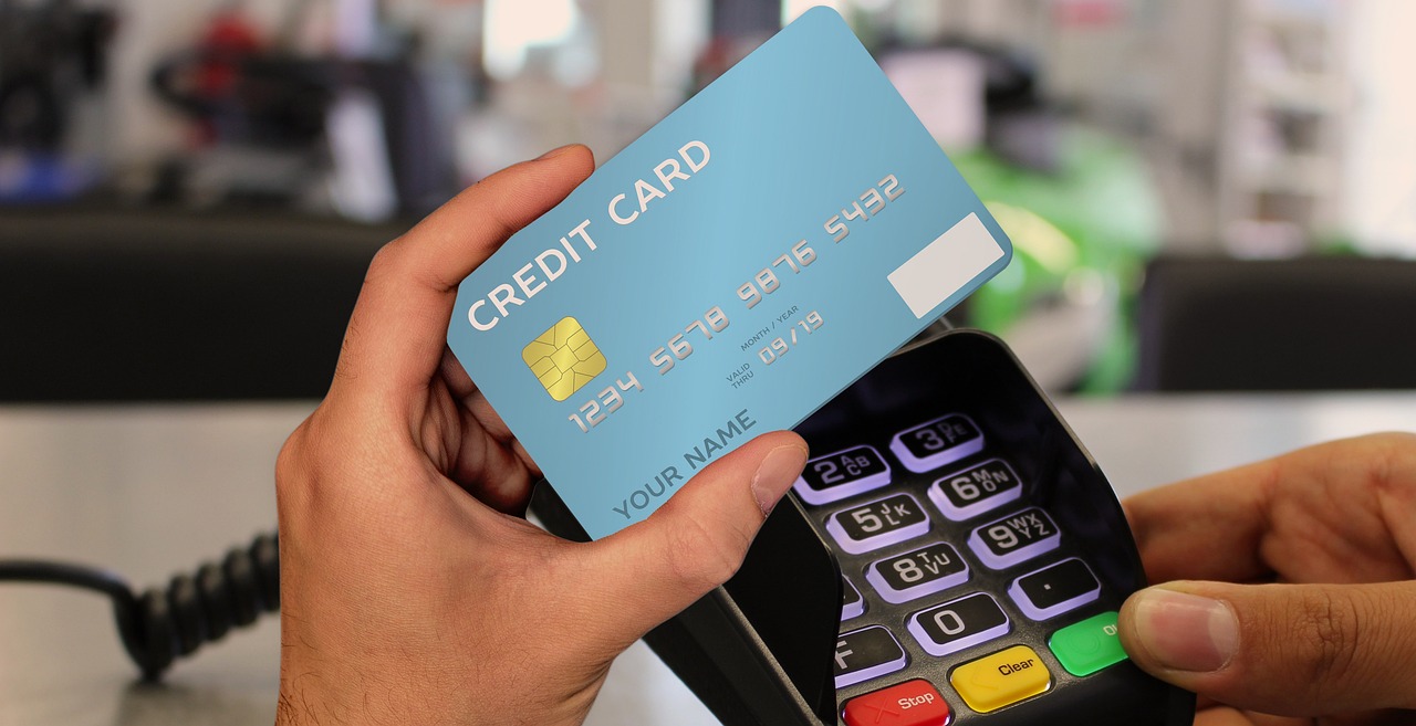 Person making a contactless payment with a blue credit card using a card reader.