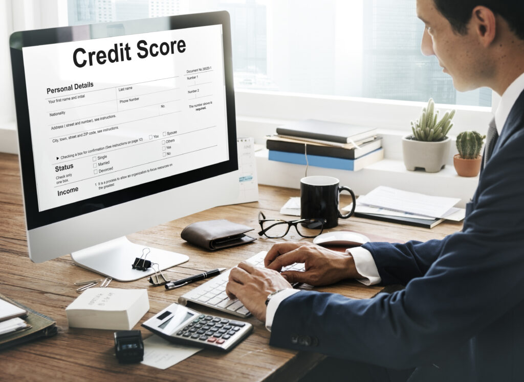 Businessman checking credit score report on a desktop computer in a modern office setting.