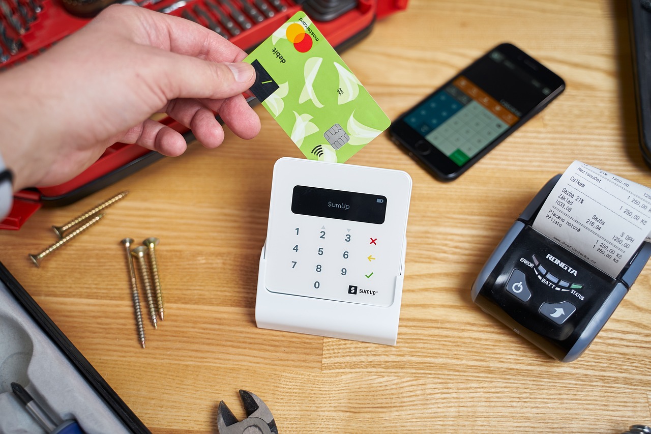 Person using a contactless payment card with a SumUp card reader in a small business or workshop environment.