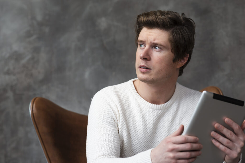 Man holding tablet while looking away
