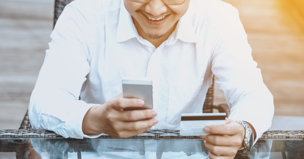 Young Handsome man enjoy shopping online on mobile phone with credit card.